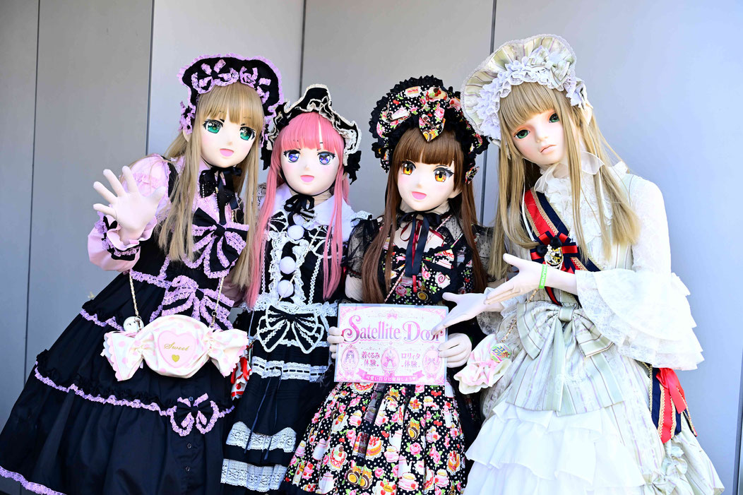 四位人脸 kigurumi 造型参与者在户外手持 Satellite Door 标牌